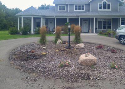 A messy landscape bed before being cleaned up by Black Brook Lawn & Landscaping