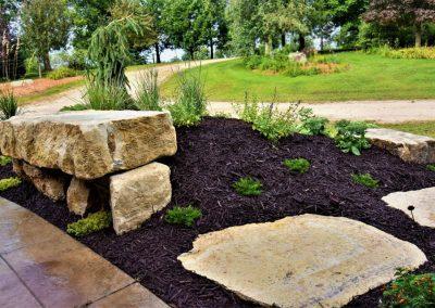A large landscape bed filled with black mulch and decorative boulders