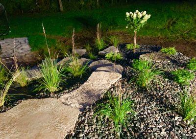 Outdoor lighting highlighting a landscape bed filled with decorative stone
