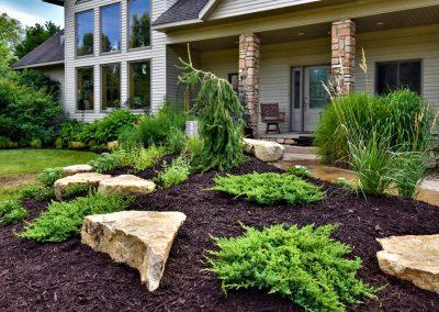 A large landscape bed filled with fresh brown mulch and decorative boulders