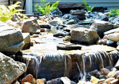 A closeup of a pondless waterfall full of natural stone