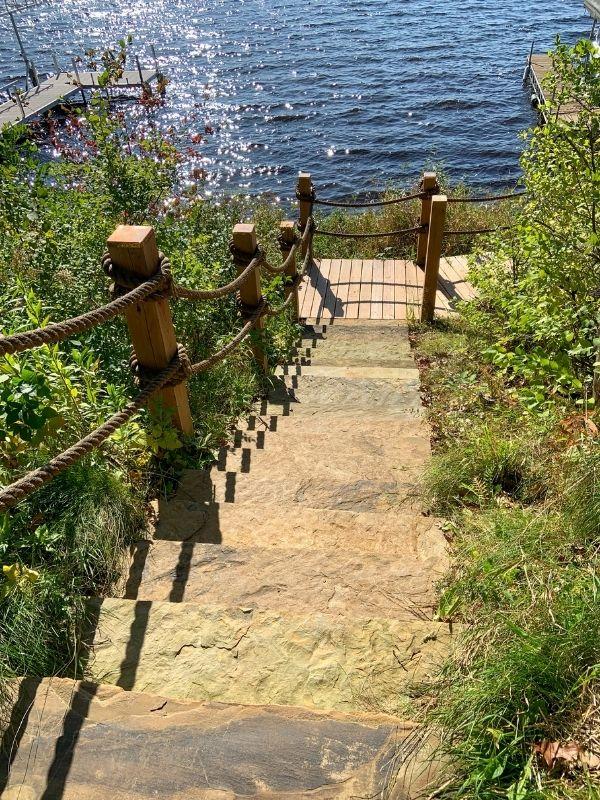 Natural stone steps leading to a wooden boardwalk lining a lake.